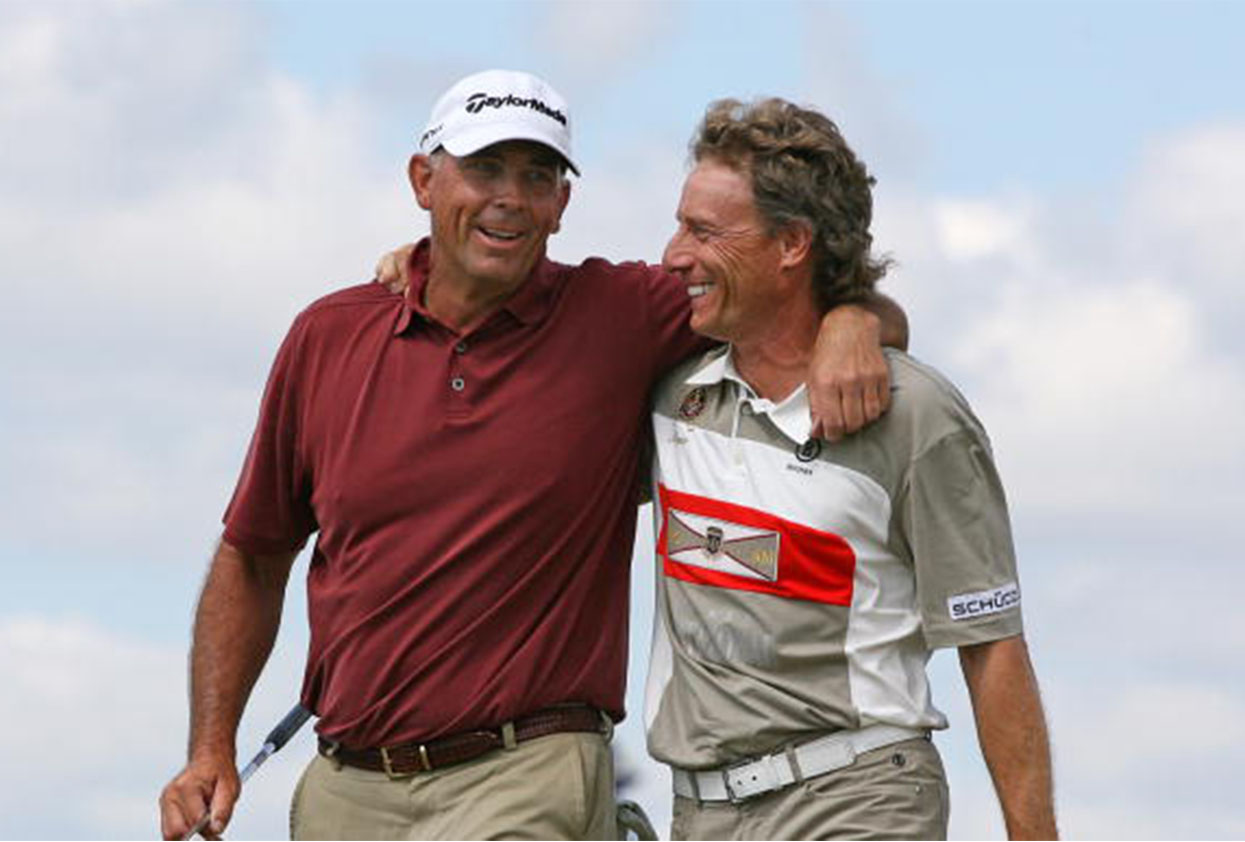 Two men are hugging and laughing on a golf course.
