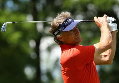 A man swinging at the golf ball on a course.